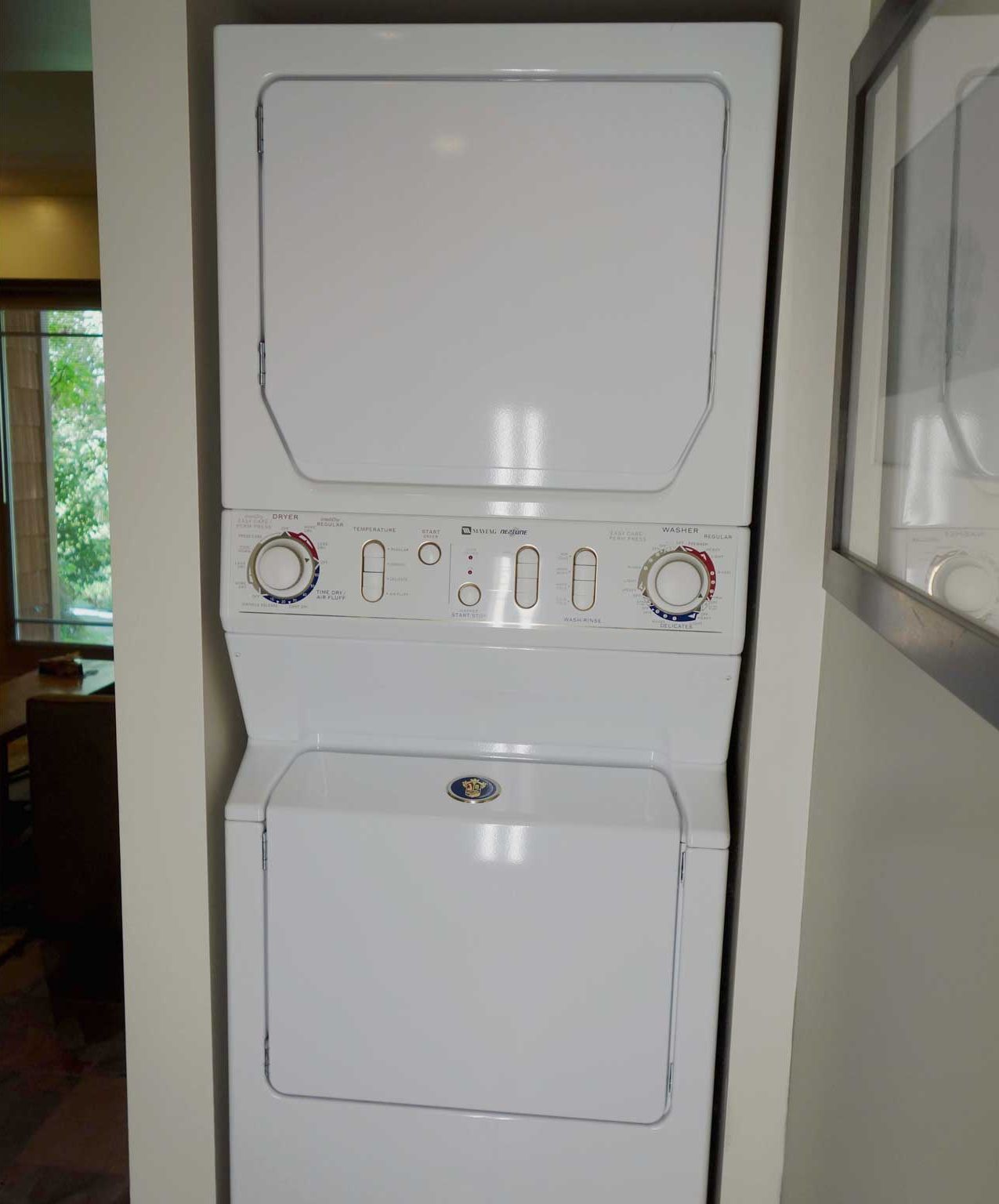 A stacked washer and dryer unit with control knobs and labels.