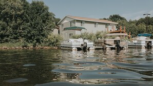 Une maison avec une jetée qui s’avance dans un fleuve paisible, entourée d’une végétation luxuriante.