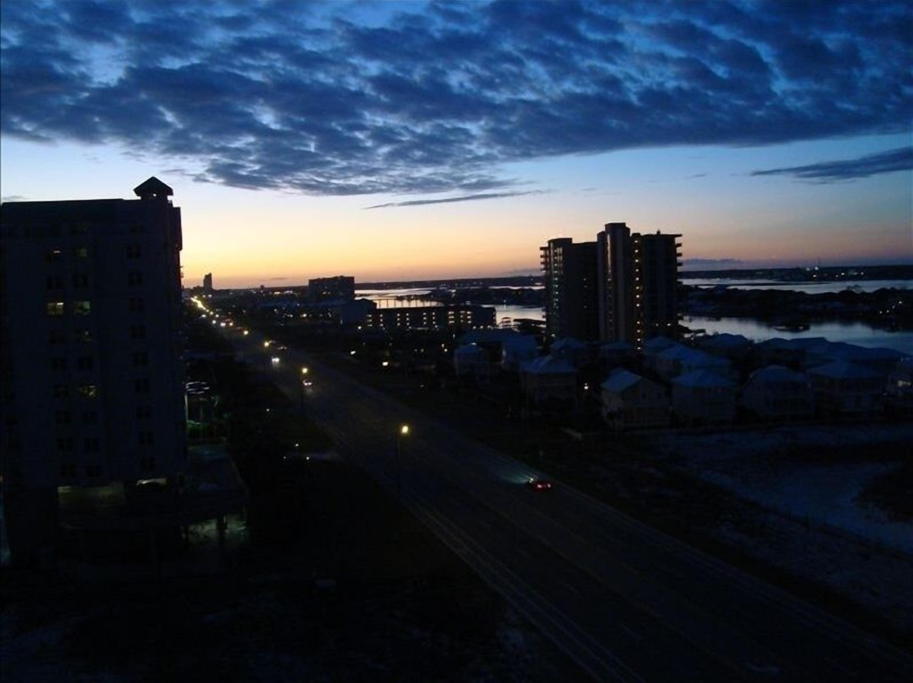 A cityscape at dusk with buildings and a road.
