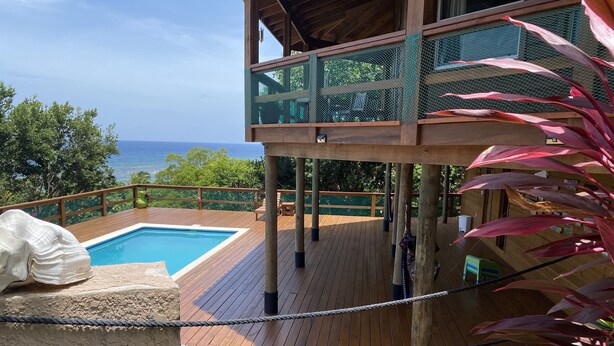 Um deck de madeira com piscina, com vista para o oceano.