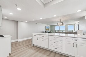 A spacious kitchen with white cabinetry, a large island, and a view to the outside.