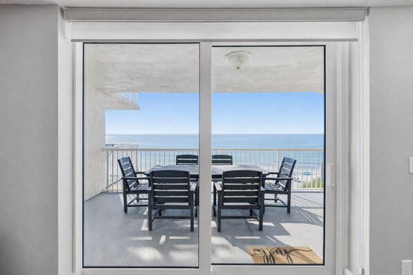 Un balcon avec une table et des chaises, donnant sur une plage.
