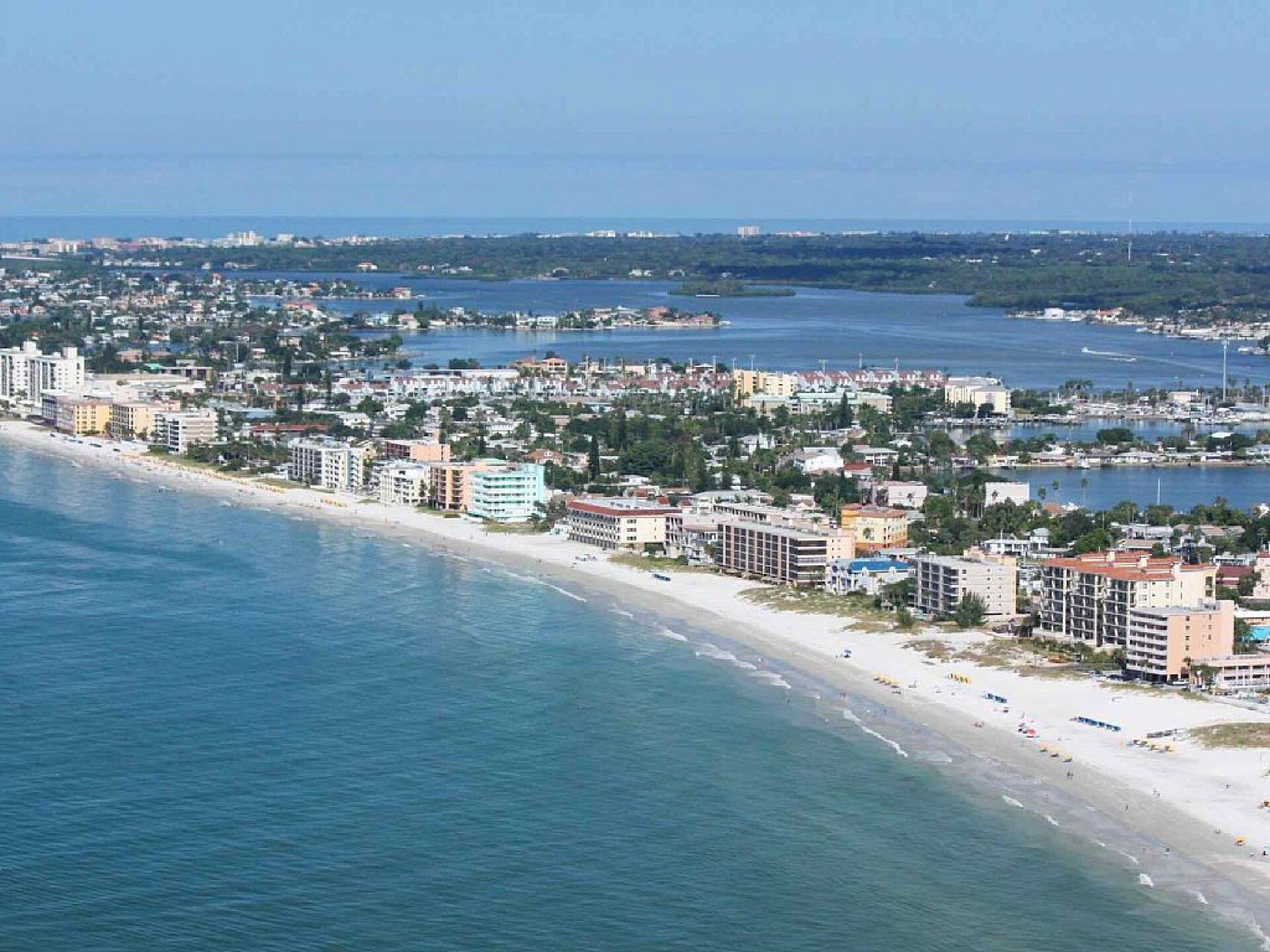 A coastal cityscape with a beachfront, high-rise buildings, and a marina.