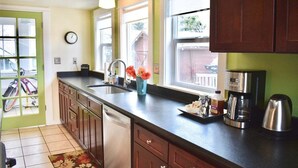 A kitchen with a dishwasher, a coffee maker, and a window with a view of the outside. - Bluebird Day - Jefferson Cottage Cozy two-bedroom, perfect for family getaways. (Bend)