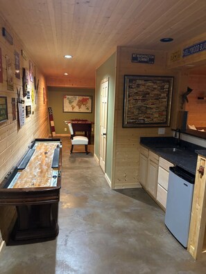 Un pasillo estrecho con una mesa de fútbol de mesa, un mapa en la pared y una puerta que da a una habitación con un lavabo y armarios.