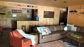 A cozy living room with a brown leather sofa, a red armchair, a coffee table, and a ceiling fan. - Dujardins waterfront lake Keowee home, with double dock on a deep, wide cove... (West Union)