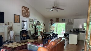 A spacious living area with a fireplace, a dining table, and a kitchen in the background. - Dujardins waterfront lake Keowee home, with double dock on a deep, wide cove... (West Union)