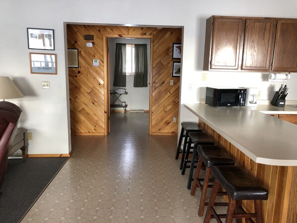 A kitchen with wooden cabinets, a microwave, and bar stools.