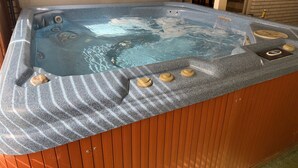 Ein Whirlpool mit Düsen, einer Steuerung und einer Steinfassade.