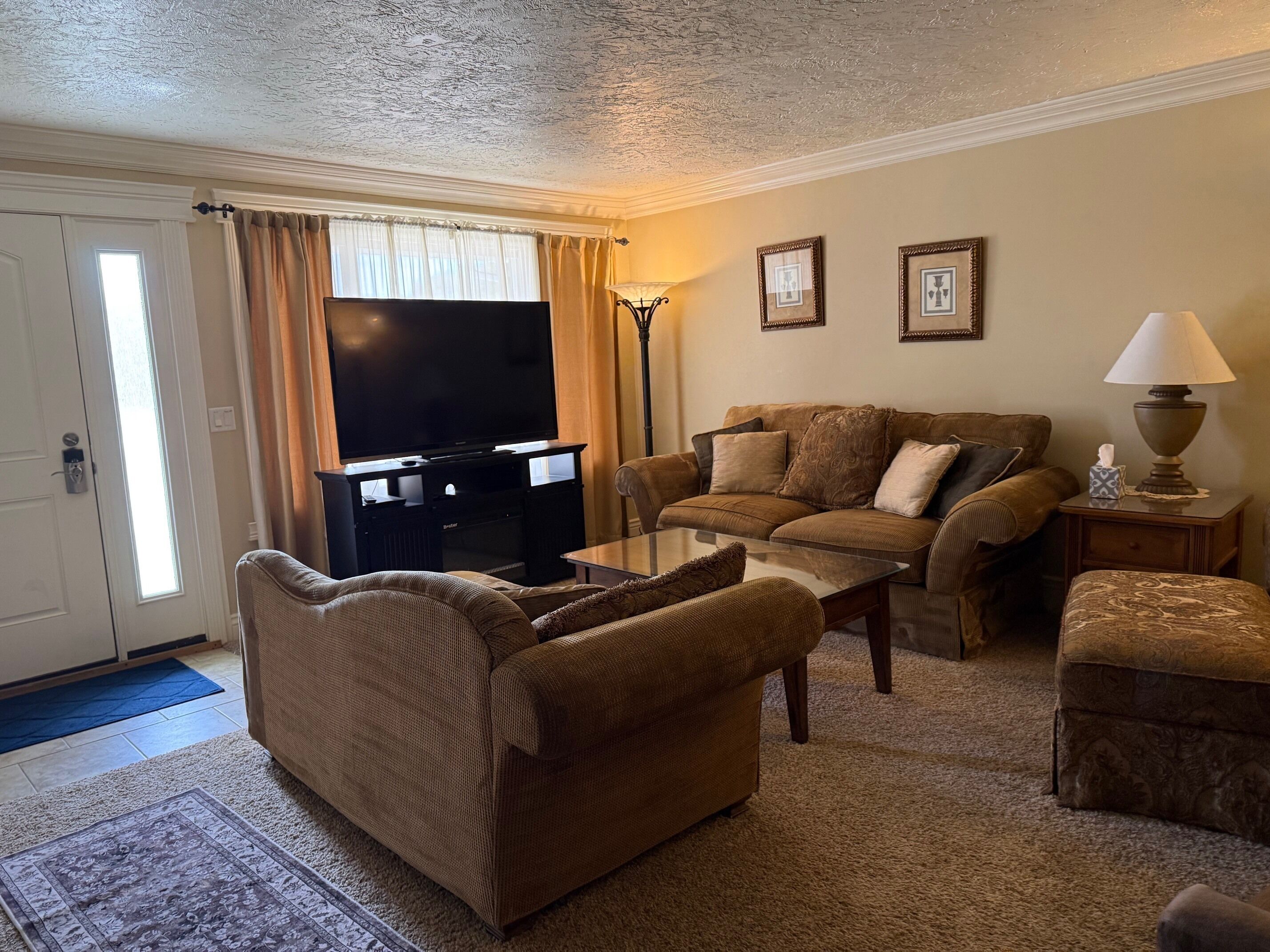A living room with a sofa, armchair, coffee table, and a television.