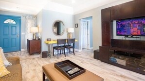 A living room with a blue door, a television, a dining area with chairs and a table, and a coffee table with a tray. - Pool and Hot Tub  Beach house 3 bedroom.. 3 bedrooms two bath.   STR19-00084 (Henderson)
