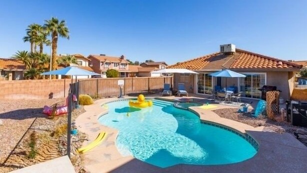 A backyard with a swimming pool, palm trees, and a house with a tiled roof. - Pool and Hot Tub  Beach house 3 bedroom.. 3 bedrooms two bath.   STR19-00084 (Henderson)
