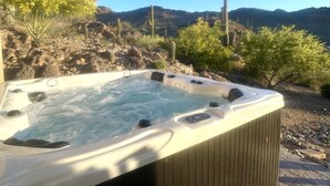 Ein Whirlpool mit Holzverkleidung, umgeben von Wüstenpflanzen und Bergen im Hintergrund.