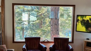 A room with two leather armchairs facing a large window with a forest view. - Serene Vistas at Northstar (Truckee)