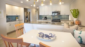 Una cocina moderna con armarios blancos, una isla central y una lámpara con bombillas expuestas.