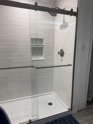 Een bad/douchecombinatie, een bubbelbad, een haardroger, handdoeken