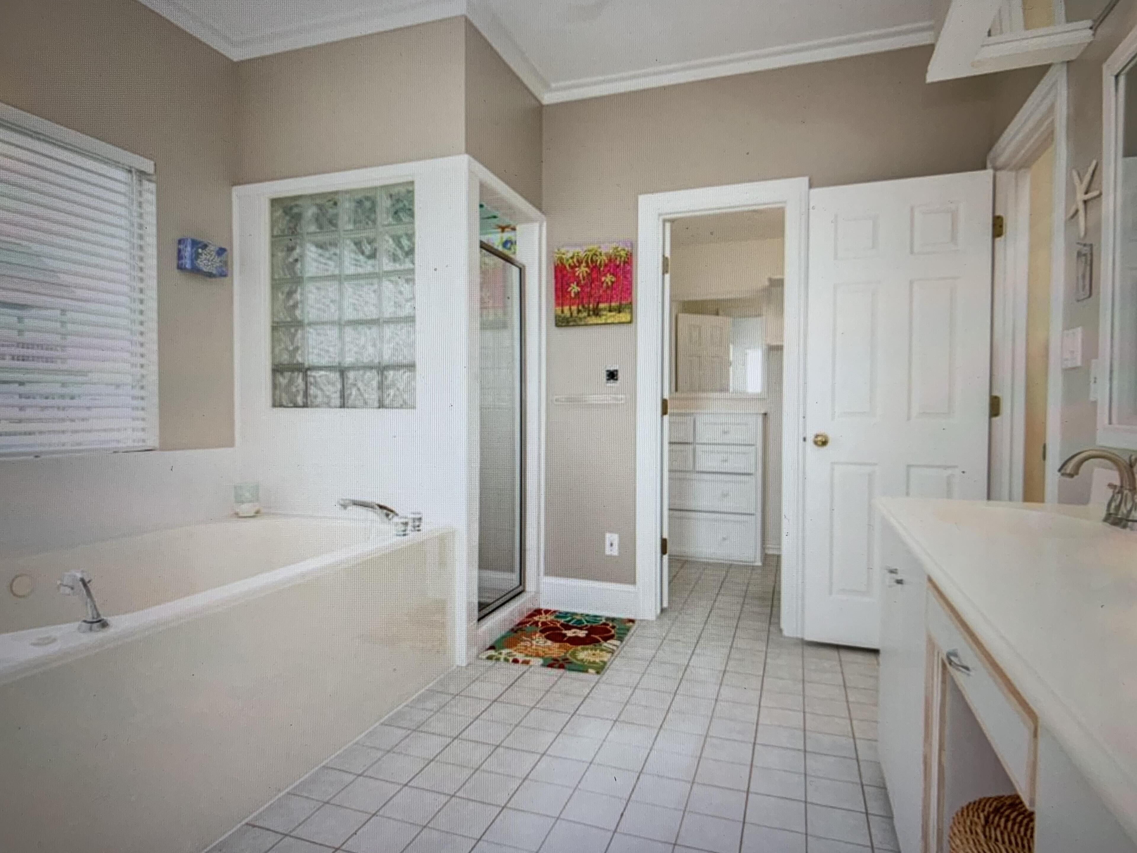 A bathroom with a bathtub, a shower, and a toilet. There is a window with blinds and a towel rack.