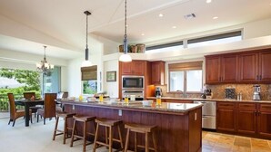 A spacious kitchen with a large island, wooden bar stools, and a dining area with a view.