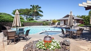 A poolside area with a table and chairs, a small fire pit, and a lounge chair.