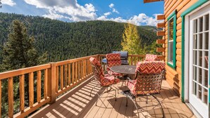 Eine Holzterrasse mit Gartenmöbeln, einem Grill und einem malerischen Bergblick.