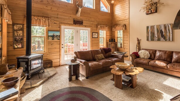 Ein gemütliches Blockhaus-Interieur mit Kamin, Ledersofas und Holzwänden.