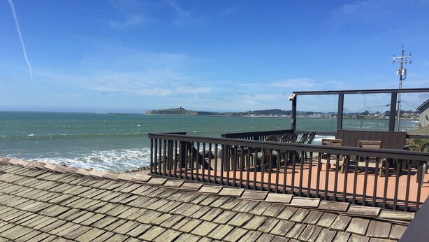 A wooden deck with a railing overlooking a beach.