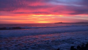 A beach with waves and a sunset.
