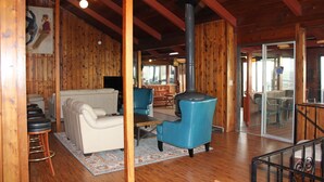 A wooden interior with a sofa, chairs, a table, and a fireplace.
