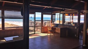 A beachside restaurant with a wooden deck, a bar area, and a view of the ocean.