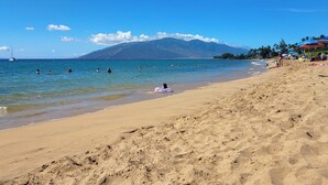 A beach with clear blue water, a sandy shore, and a mountain in the background. - Aloha Kai-Private Ocean View Condo in Kihei Steps to the Beach! (Kihei)