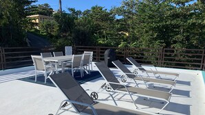 Zona junto a la piscina con sillones de descanso y una mesa.
