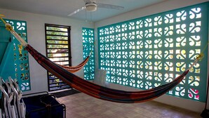 Una habitación con hamaca, ventilador de techo, ventana con vistas y un adornado en la pared.