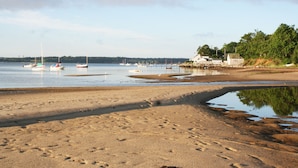 A sandy beach with boats, a pier, and a building with a flag. - Luxury 7 BR, 4 BA w/ Unique 60 ft Pool, .4 Miles to Beach (Orleans)