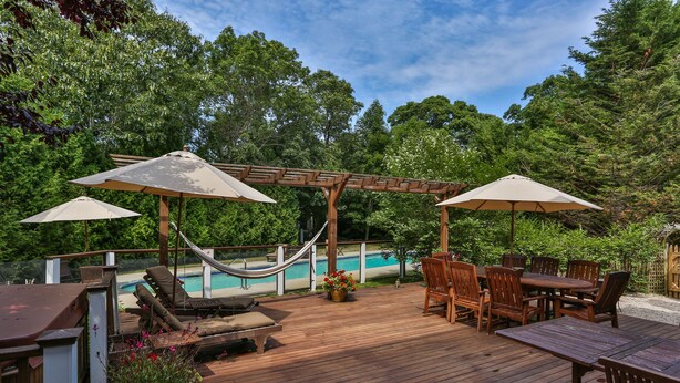 A wooden deck with outdoor furniture, a hammock, and a pool in the background. - Luxury 7 BR, 4 BA w/ Unique 60 ft Pool, .4 Miles to Beach (Orleans)