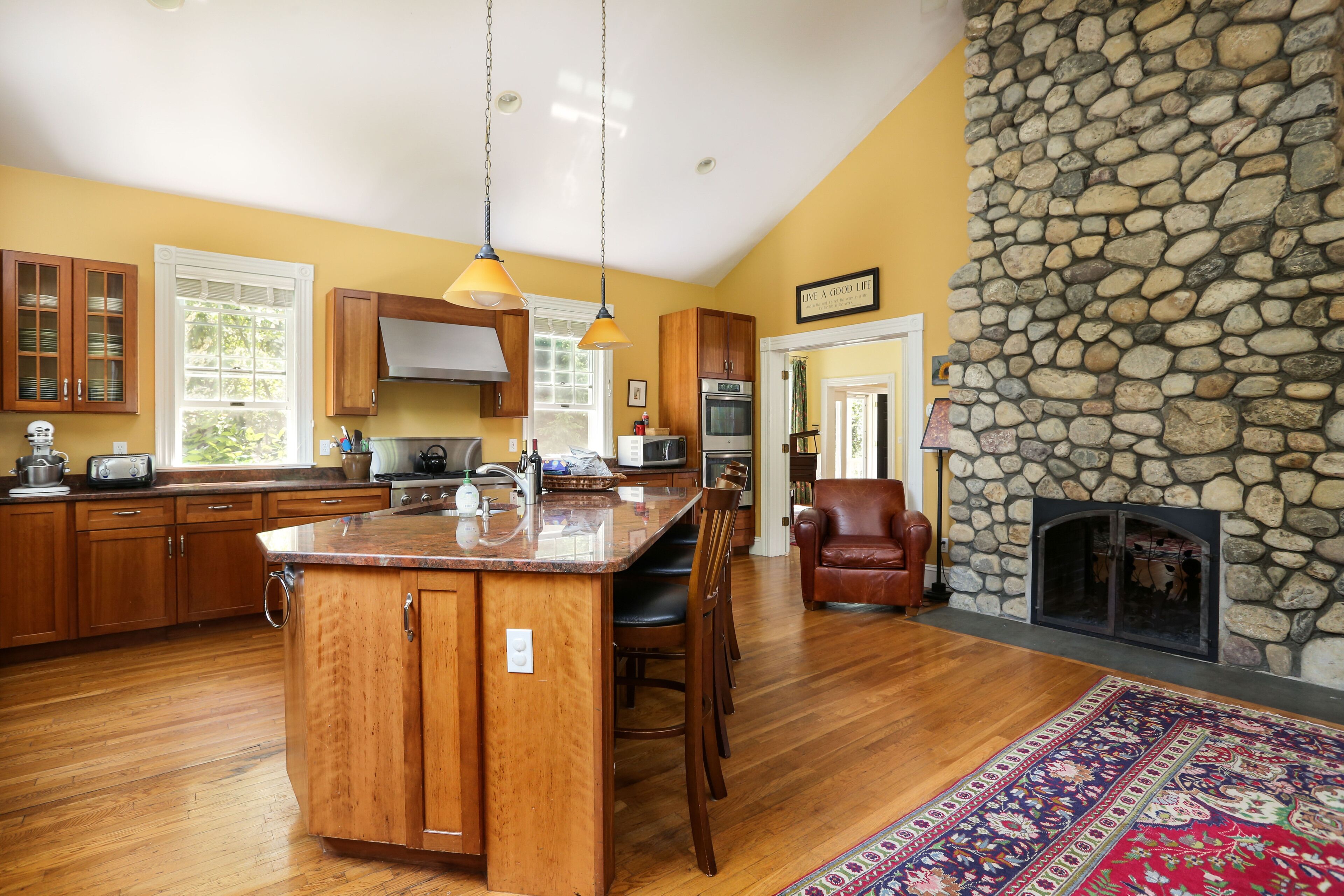 Una cocina con armarios de madera, una isla central y una chimenea de piedra.
