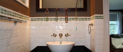A bathroom with a white sink, a mirror above it, and a tiled backsplash.