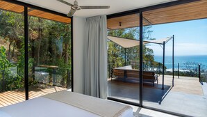 Une chambre moderne dotée d’une grande fenêtre, d’un ventilateur de plafond et offrant une vue sur l’océan.
