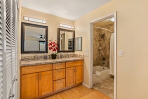 A bathroom with wooden cabinets, a granite countertop, a mirror, a shower, and a toilet. - Oceanview, no stairs and a Murphy Bed at Maui Kam (Kihei)