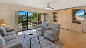 A modern living room with a sofa, armchairs, a coffee table, and a TV. - Rare No-Stairs Ocean View Condo ~ Maui Kamaole (Kihei)