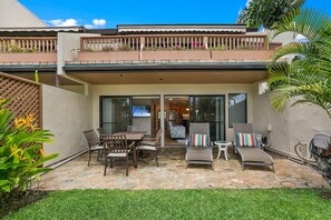 Une terrasse avec une table et des chaises, un fauteuil de relaxation et une petite table d’appoint.