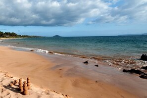 A beach with sand, water, and a mountain in the distance. - Oceanview, no stairs and a Murphy Bed at Maui Kam (Kihei)