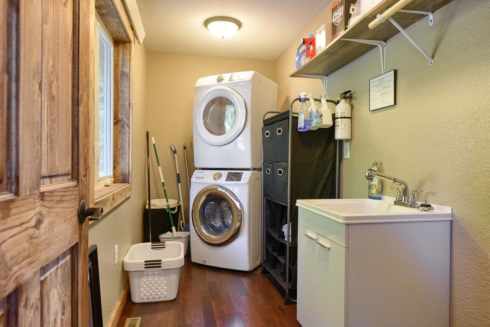 A compact laundry room with a washing machine, dryer, and a sink.