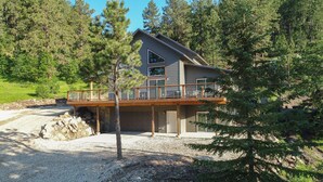 A two-story house with a balcony, surrounded by trees. - Lazy Dog Lodge, Hot Tub, AC & Activities Near Black Hills (Lead)