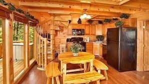 L’intérieur d’une cabane en bois comprend un coin repas, une cuisine et de grandes fenêtres.