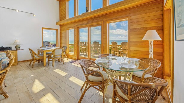Ein geräumiger Balkon mit Korbmöbeln und Glastischen mit Blick aufs Meer.