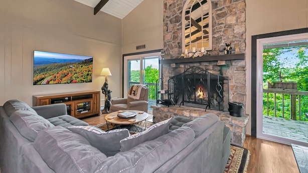 A living room with a stone fireplace, a large flat-screen TV, and a sofa.