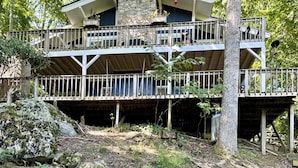 A two-story lodge with a stone facade, multiple balconies, and a wooden deck.