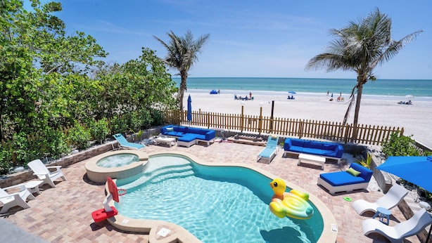 Un espace piscine avec des chaises longues, un jacuzzi et une vue sur la plage.
