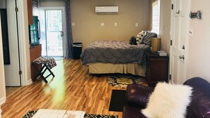 A bedroom with a bed, a dresser, a chair, a small table, and a door. - Relaxing Cottage close to everything! Perfect for 2!Wi-Fi, Keurig,Outside space! (Greensboro)