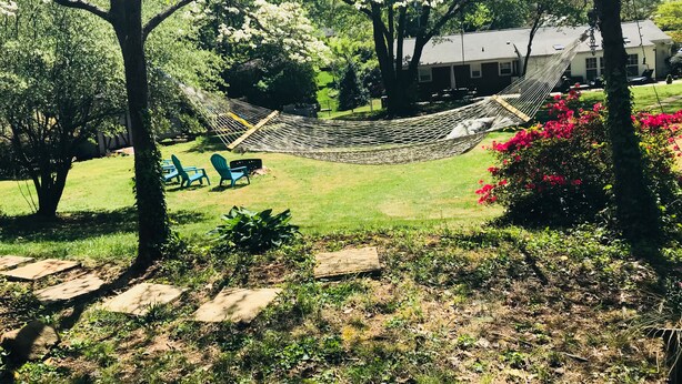 A hammock between trees in a grassy area with a house in the background. - Relaxing Cottage close to everything! Perfect for 2!Wi-Fi, Keurig,Outside space! (Greensboro)